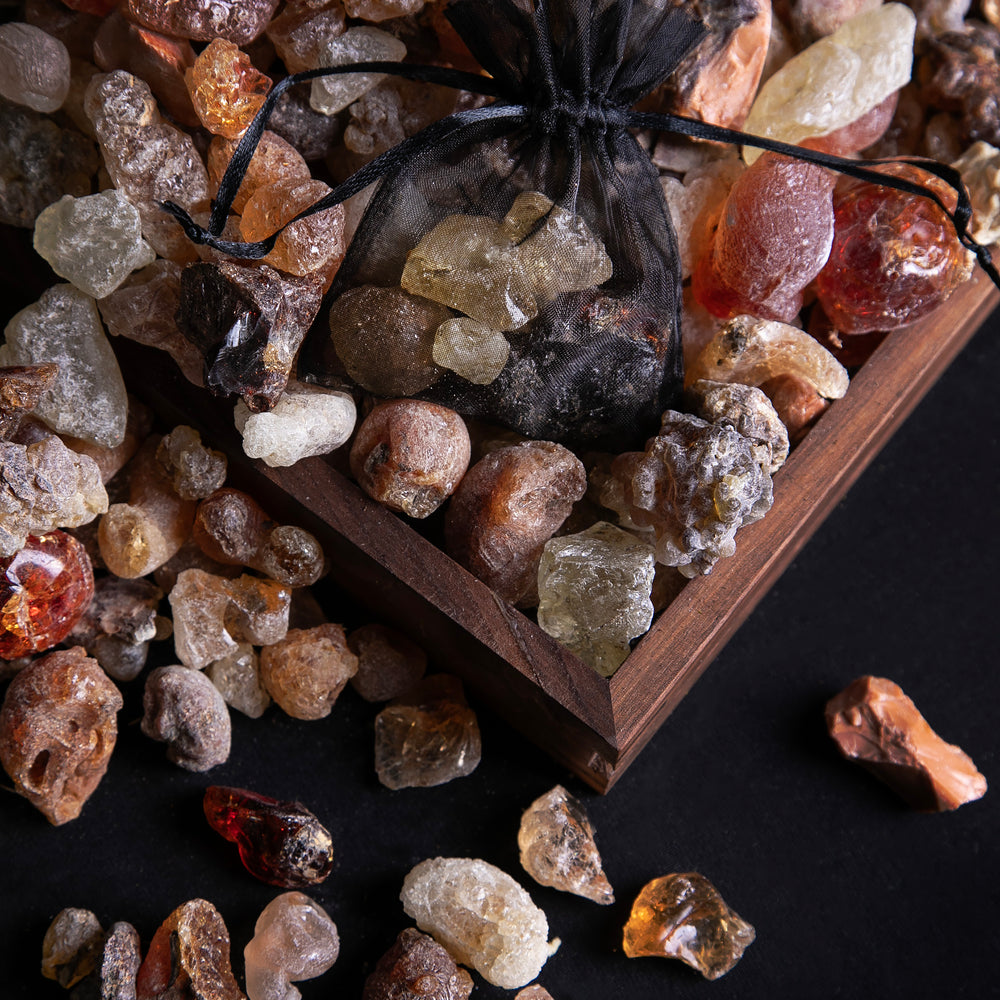 
                      
                        shards of amber-coloured resin piled upon and scattered around a wooden frame against a black background
                      
                    