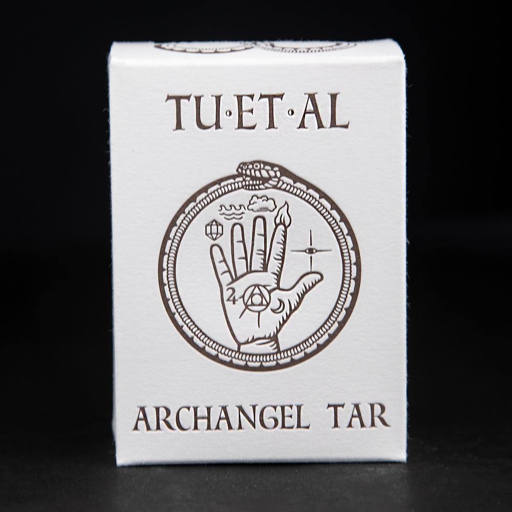 Box of TU-ET-AL's "archangel tar" soap against a black background. The box features an illustration of a snake eating its own tail and an alchemical hand in dark brown