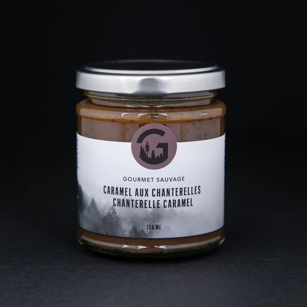 Clear glass jar with metal screw top lid containing chantelle caramel by "Gourmet Sauvage", sitting on black background