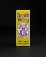 Death Valley Nails box against black background, the box is chartreuse coloured with vintage-inspired purple lettering and illustrations