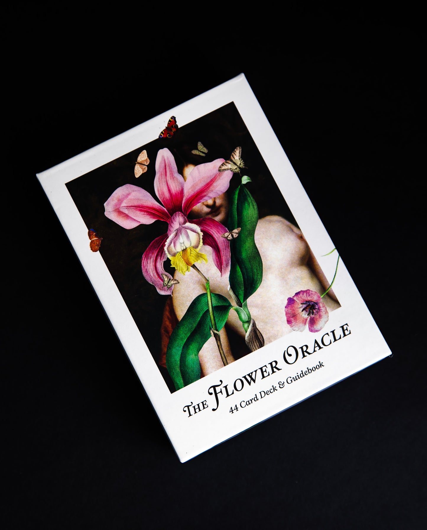 Box of Brocolli's "The Flower Oracle" deck sitting on black background, with a collage of floral botanical illustrations on the cover.