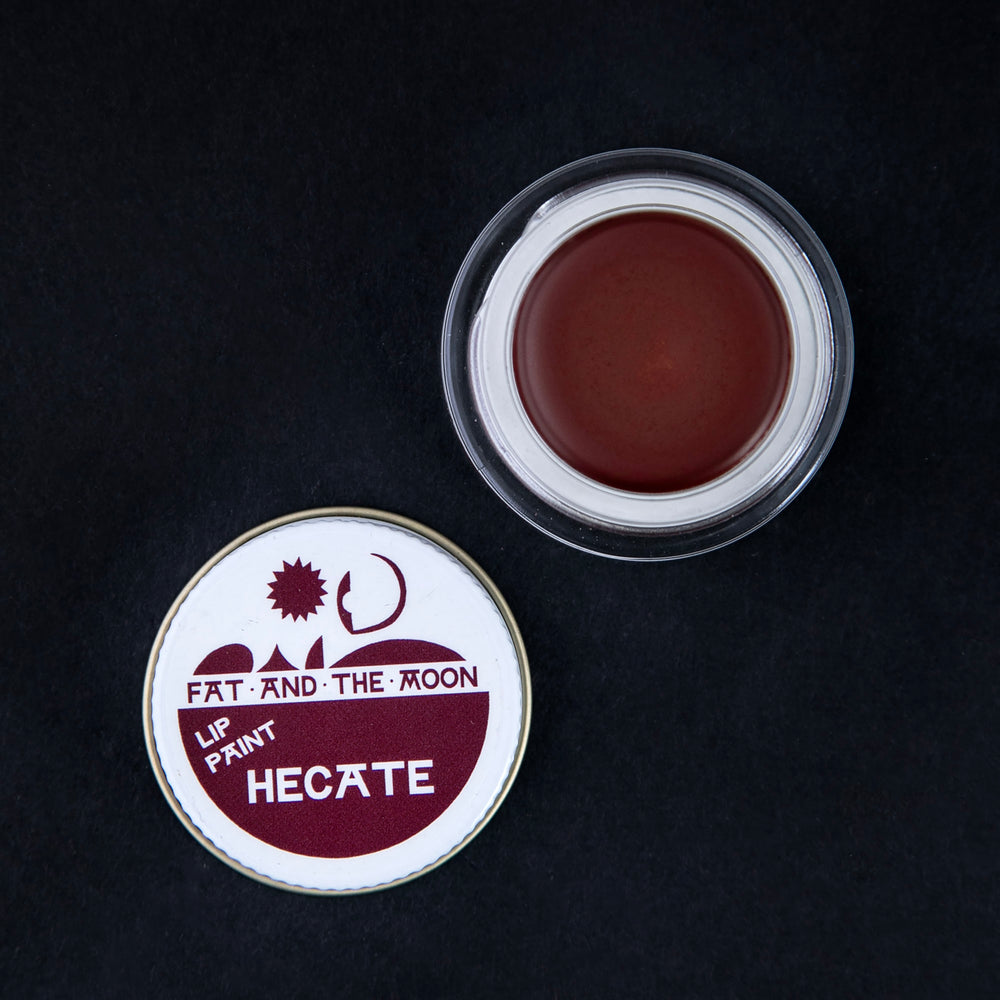 open glass pot of Fat and the Moon "Hecate" lip paint, revealing a deep wine red lip colour