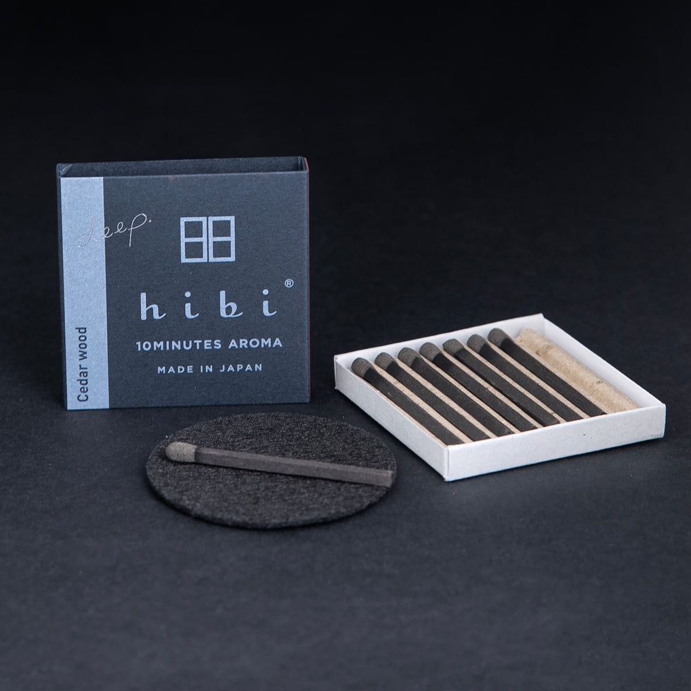 
                      
                        open box of HIBI incense matches, individual matches are nestled in a corrugated cardboard insert, a match is sitting on a small heatproof burn mat
                      
                    