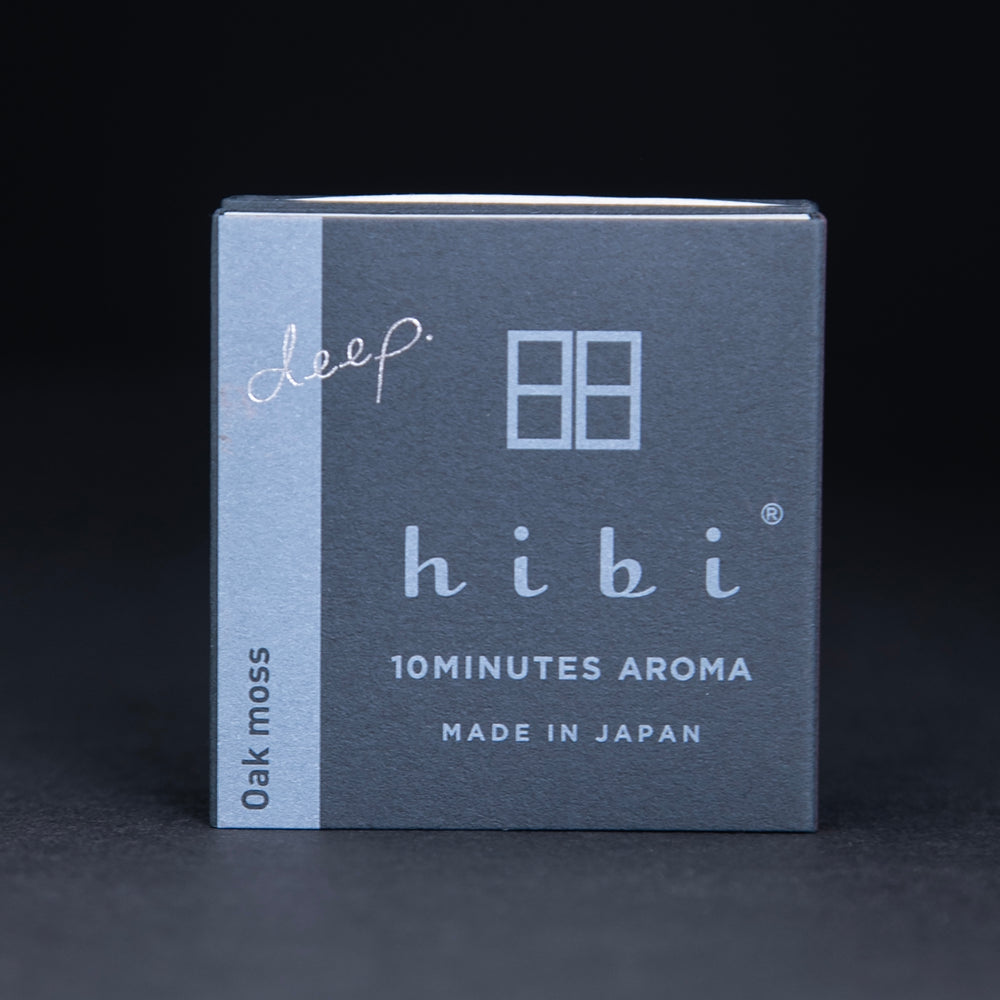 Dark slate grey paper box containing HIBI "oakmoss" incense matches, sitting on black background