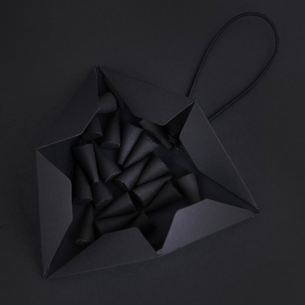 open black triangular incense box on black background