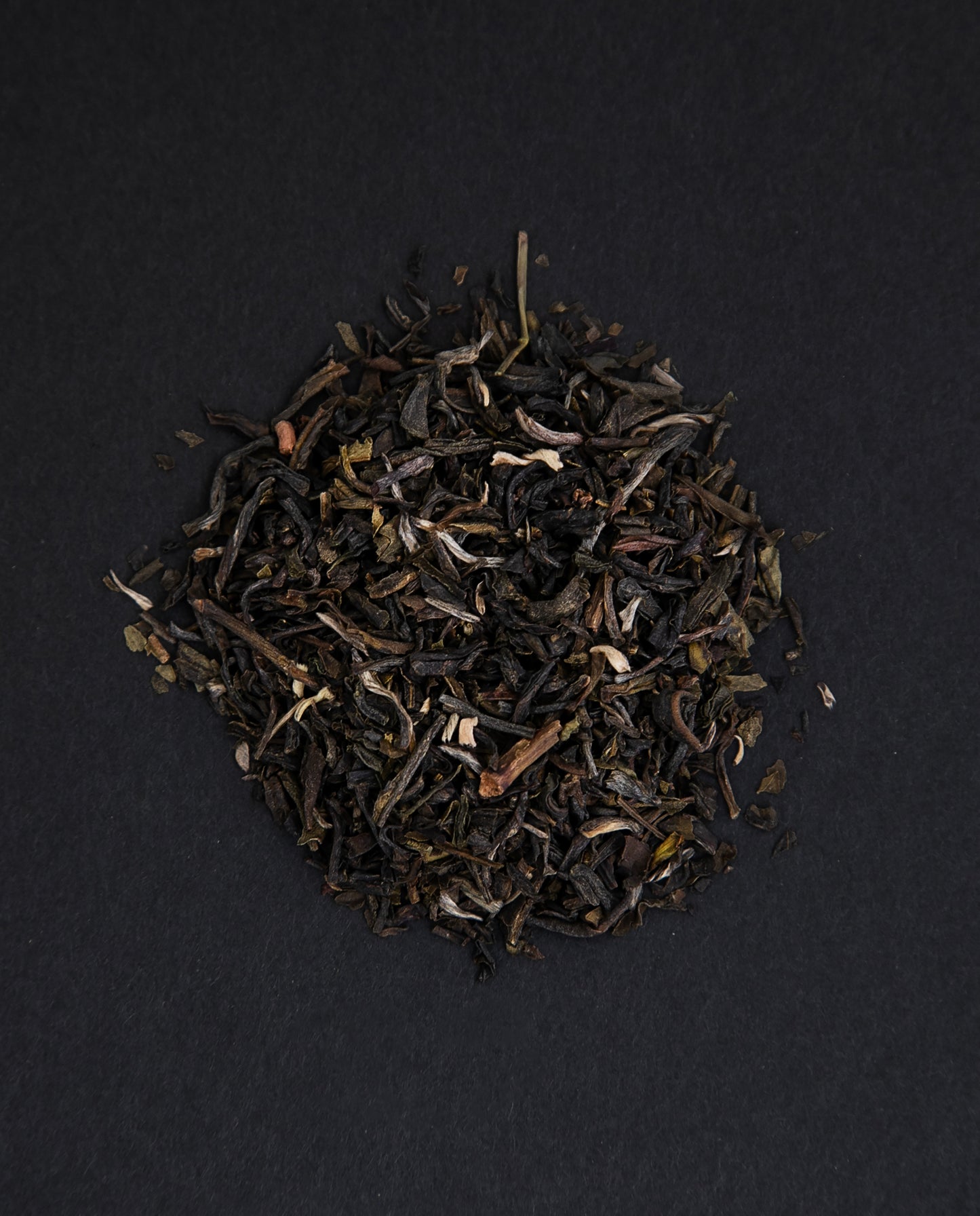 small pile of "jasmin mandarin" tea viewed from above against a black background