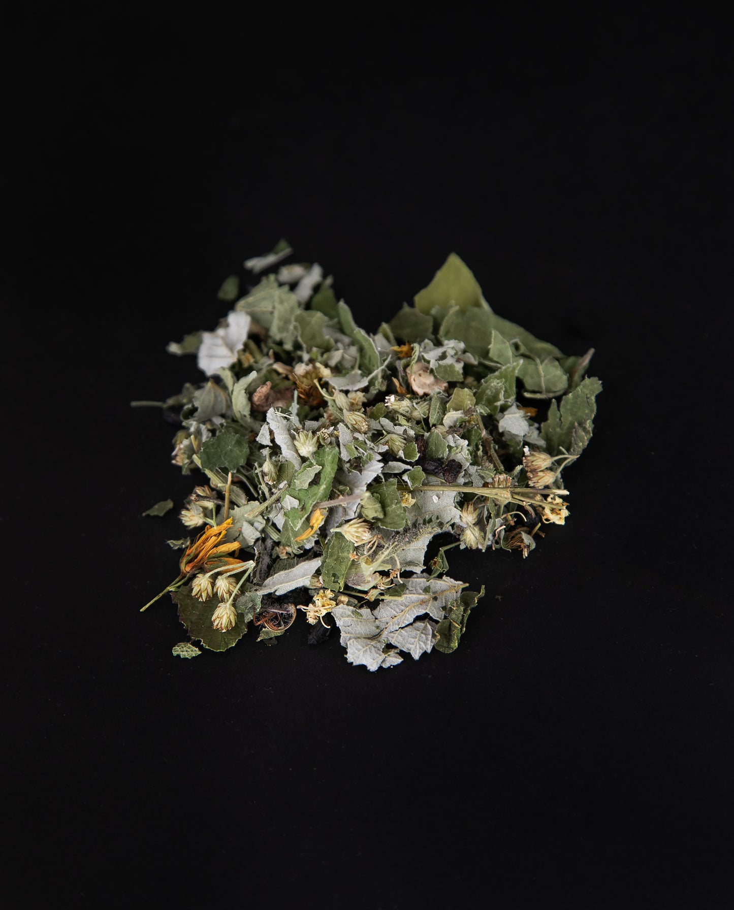 handful of l'Équinoxe loose leaf herbal tea on a black background