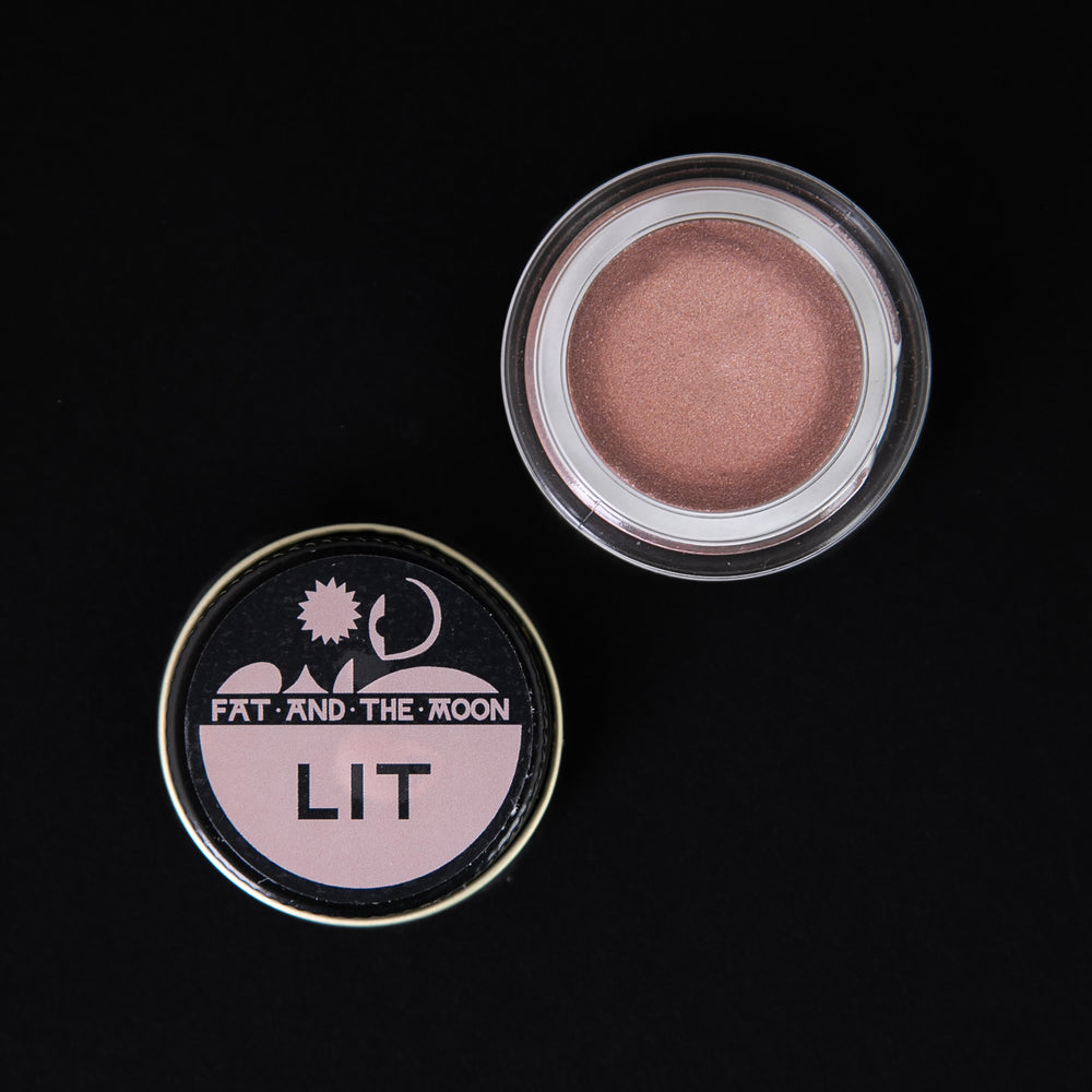 Glass jar of Fat and the Moon's "Lit" highlighter, open to reveal a shimmering dusty rose.