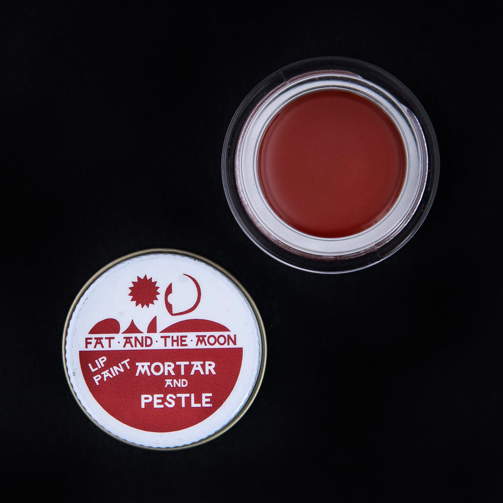 glass pot of Fat and the Moon "Mortar & Pestle" lip paint open, revealing a brick red lip colour