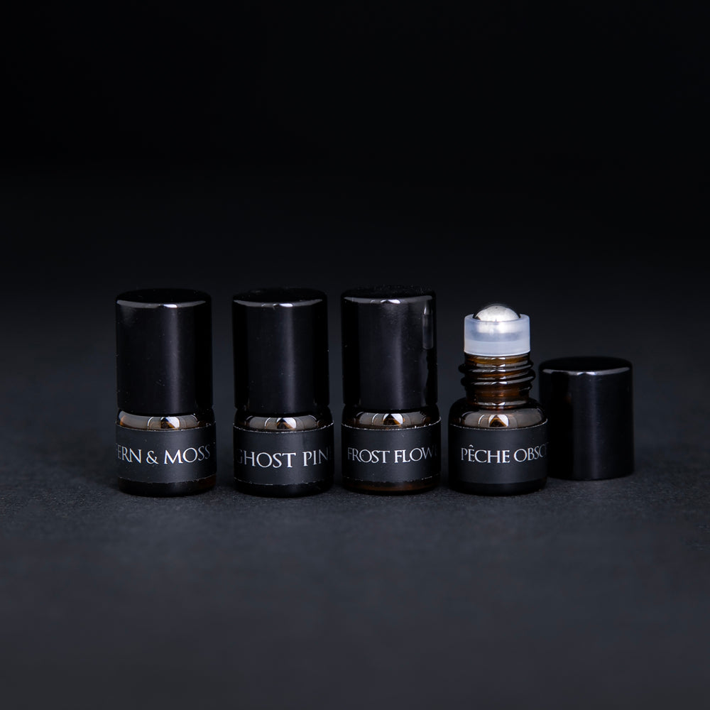 
                      
                        Four amber glass 1.25ml parfum botanique sample lined up on a black background. The last bottle's cap is open, revealing a metal roller ball top.
                      
                    