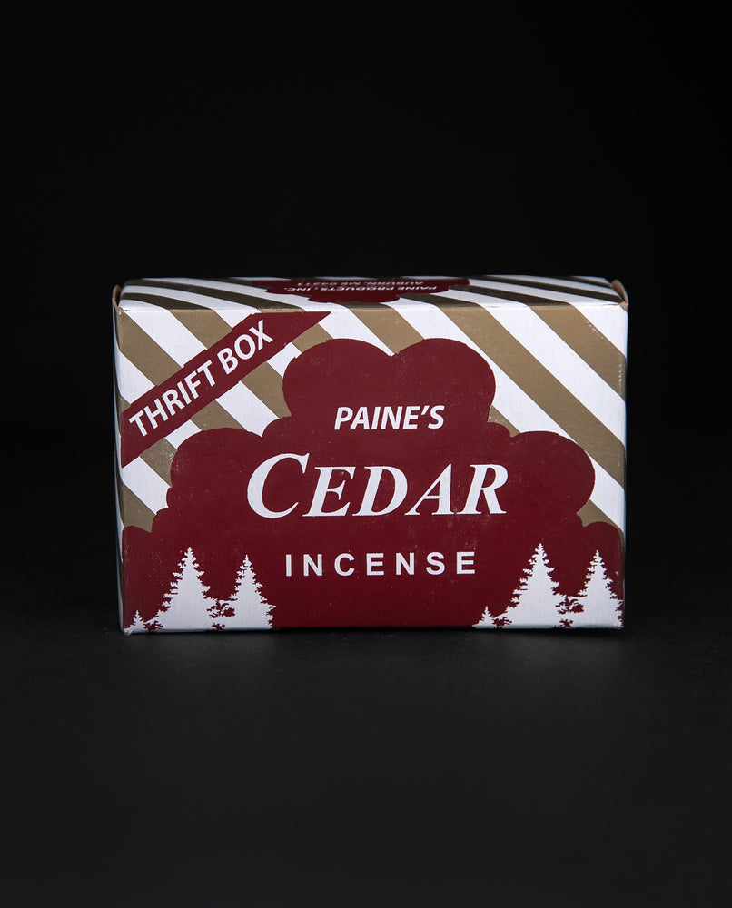 Closed box of Paine's Red Cedar Incense cones. The paper box is deep red, gold, and white with silhouetted illustrations of cedars