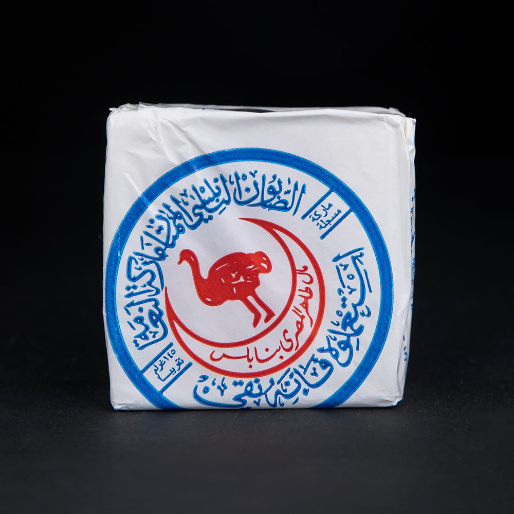 Bar of Palestinian olive oil soap wrapped in white wax paper, stamped with a blue and red ostrich seal