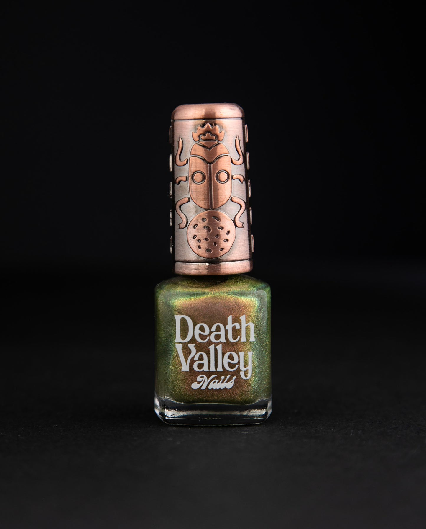 Bottle of "Eating Heads" nail polish on black background. The polish has a green base with multichrome shimmery finish.