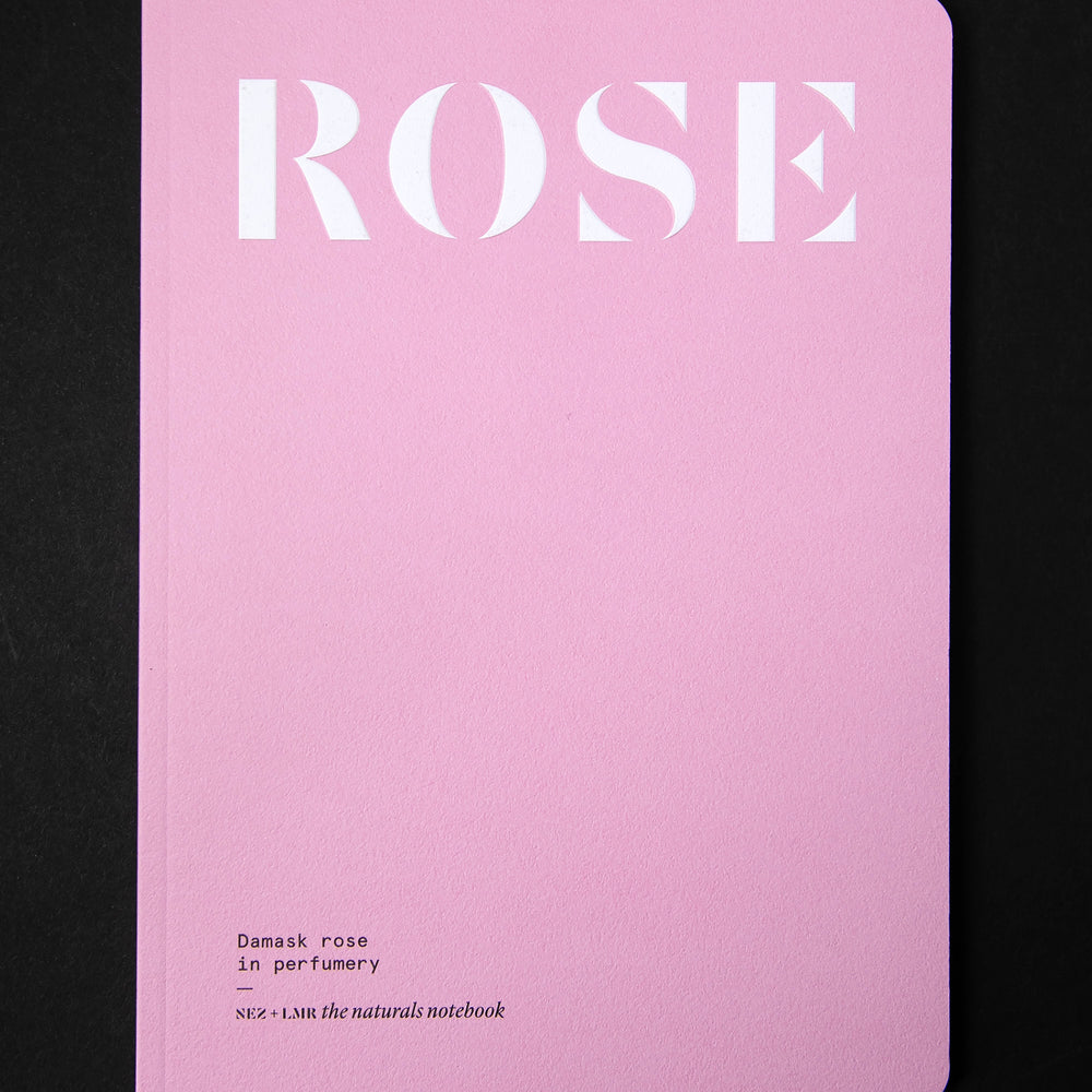 "Damask Rose in Perfumery" book on black background. The cover is flat pink and reads "ROSE" in a big bold font. 