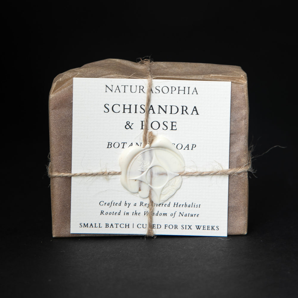 
                      
                        Bar of Naturasophia soap wrapped in brown paper and twine, with a label that reads "Schisandra & Rose". There is a white wax stamp holding the label in place.
                      
                    