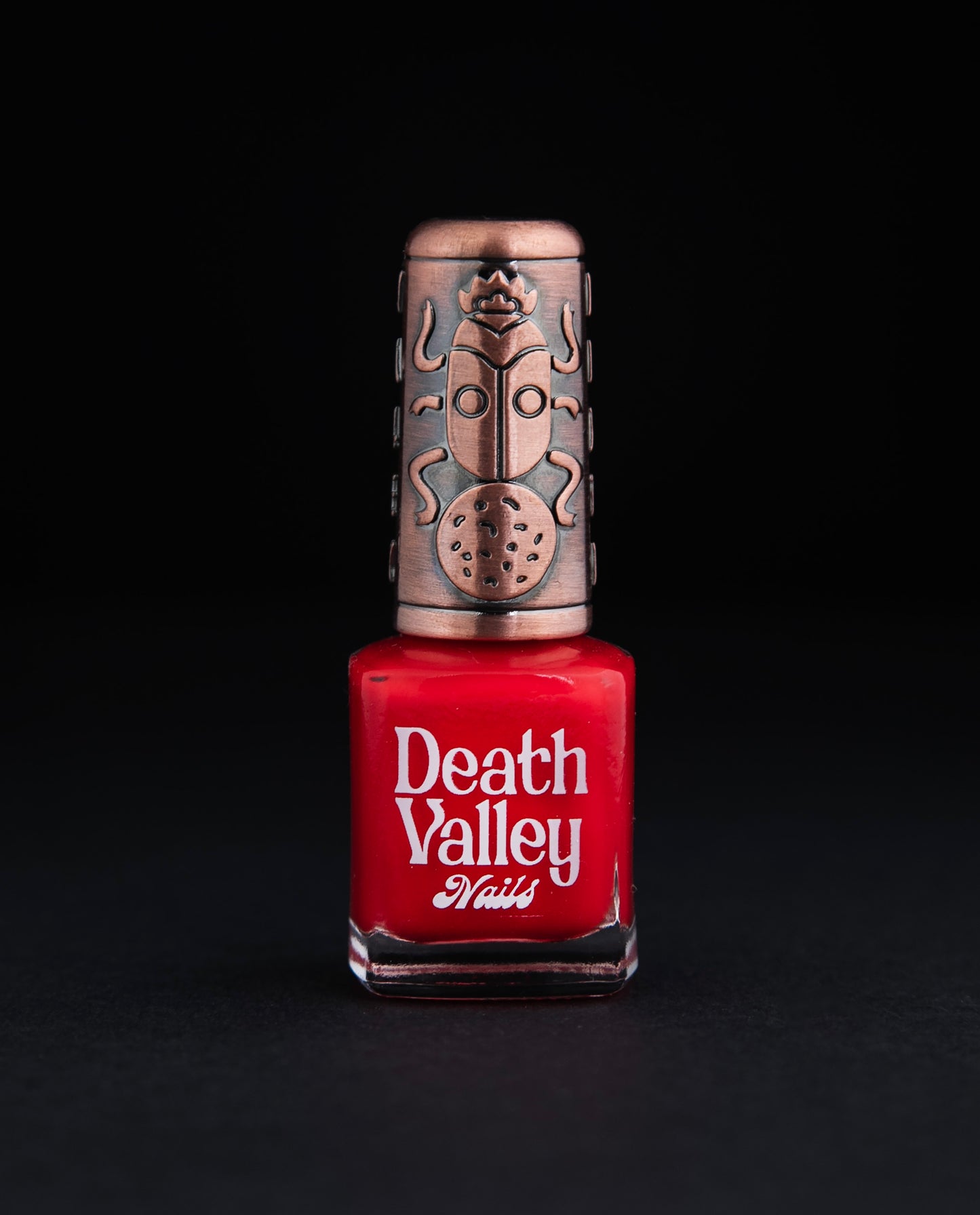 Bottle of "Shrimps" nailpolish on black background. The polish colour is a vibrant true red.