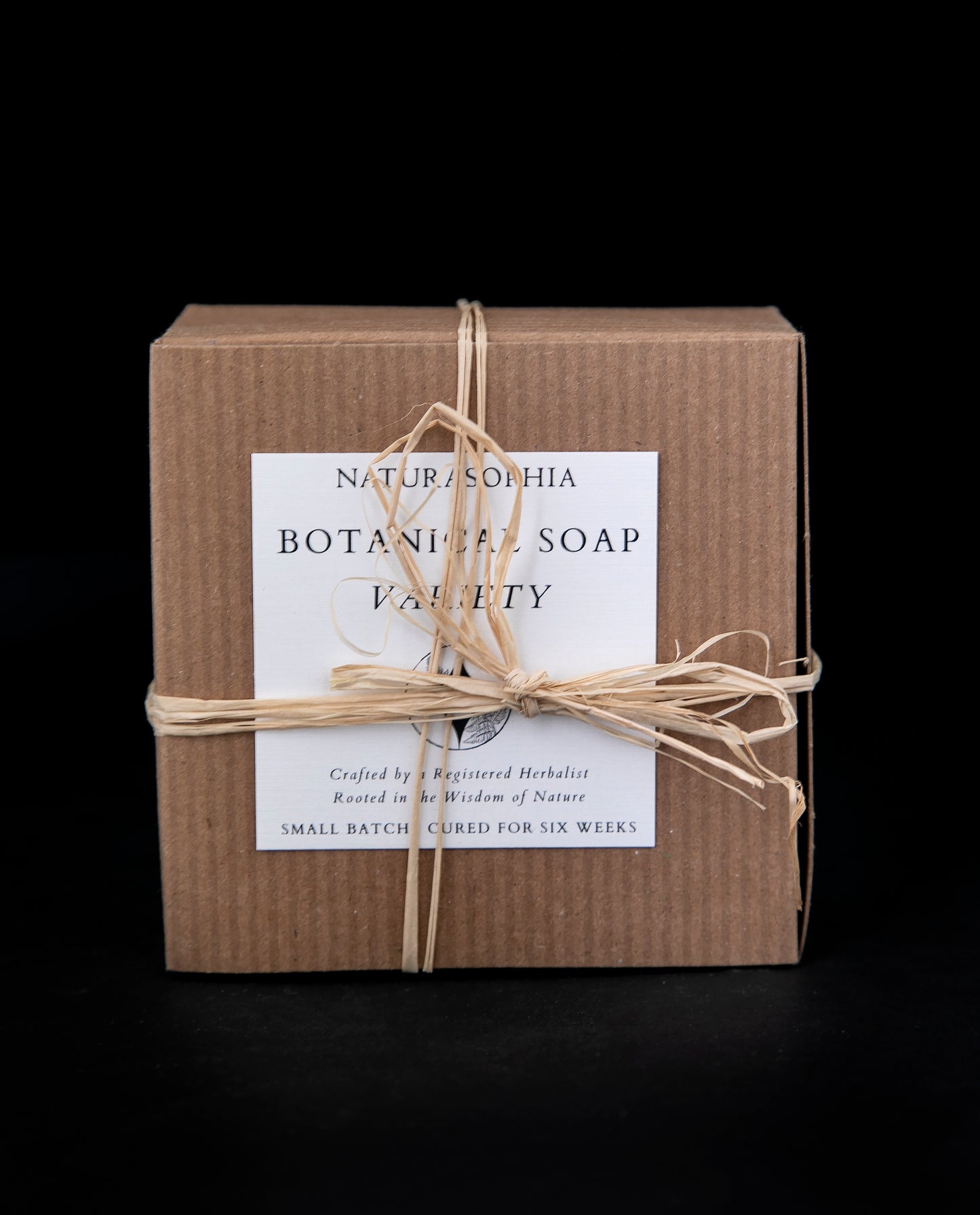 natural cardboard gift box wrapped with a raffia bow, contains a varied assortment of Naturasophia botanical soaps 