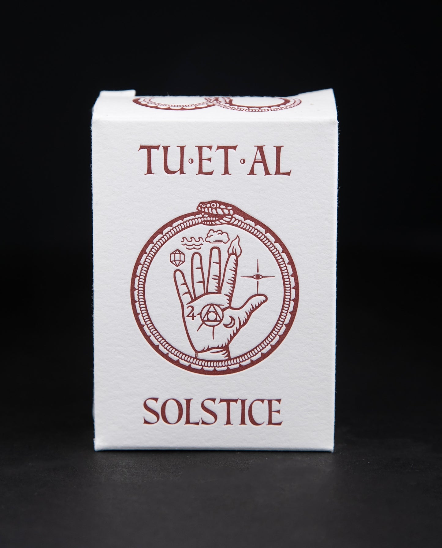 White cardboard soap box containing TU-ET-AL's "Solstice" soap. There is an illustration of a snake eating it's own tail, and an alchemical hand on front in brown.