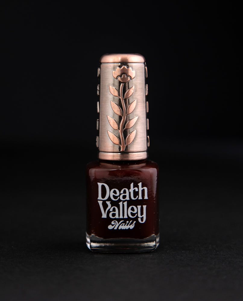 "Swamp Sparrow" nail polish by Death Valley Nails on black background. The polish is a deep cherry red colour with a jelly finish.