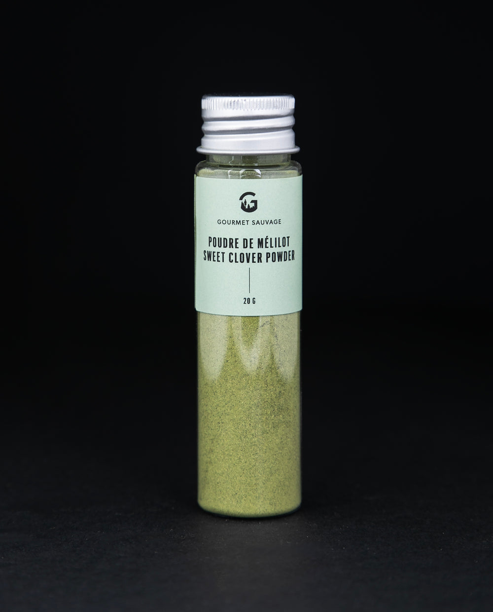 Clear tube of Gourmet Sauvage's sweet clover powder, sitting on black background. The powder is a vibrant green colour.