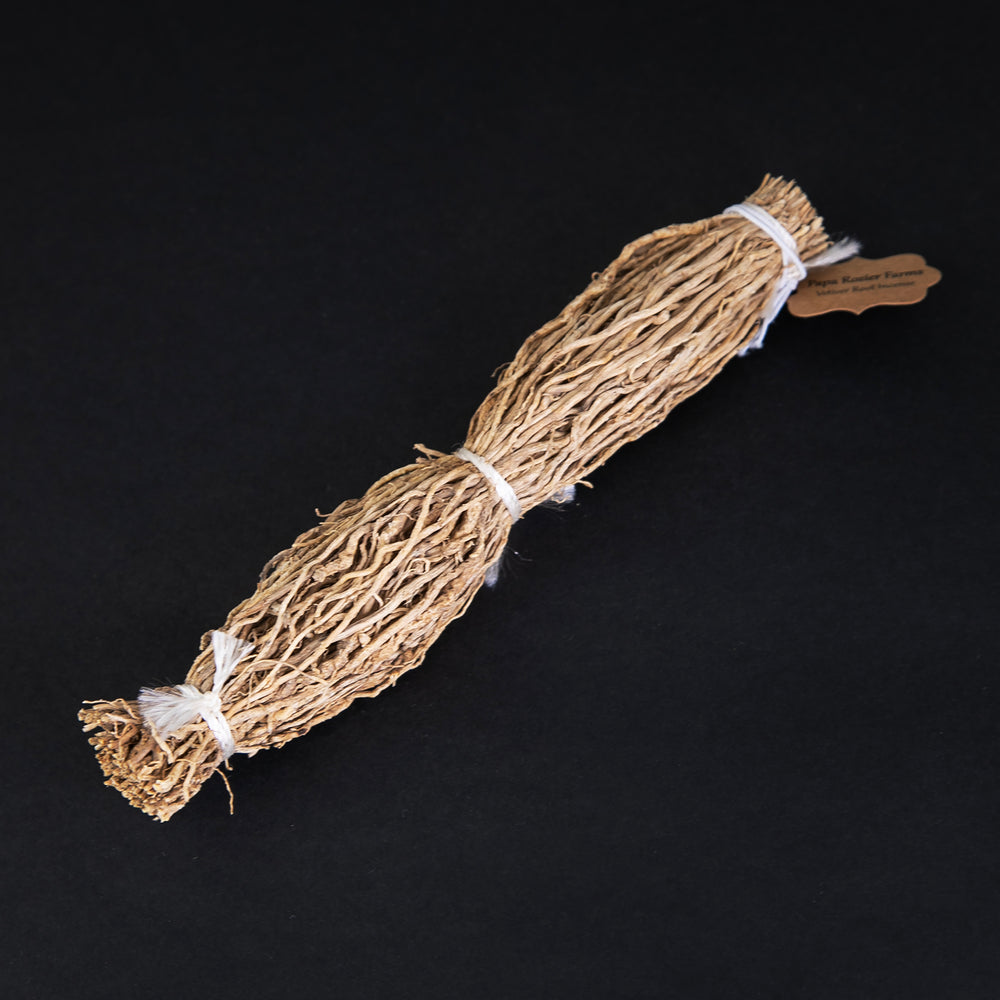 6 inch long bundle of vetiver root tied up with white twine, sitting on a black background