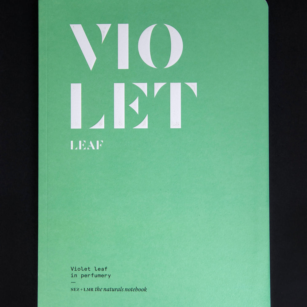 "Violet Leaf in Perfumery" book against a black background. The cover is spring green with the words "violet leaf" written in bold white graphic text