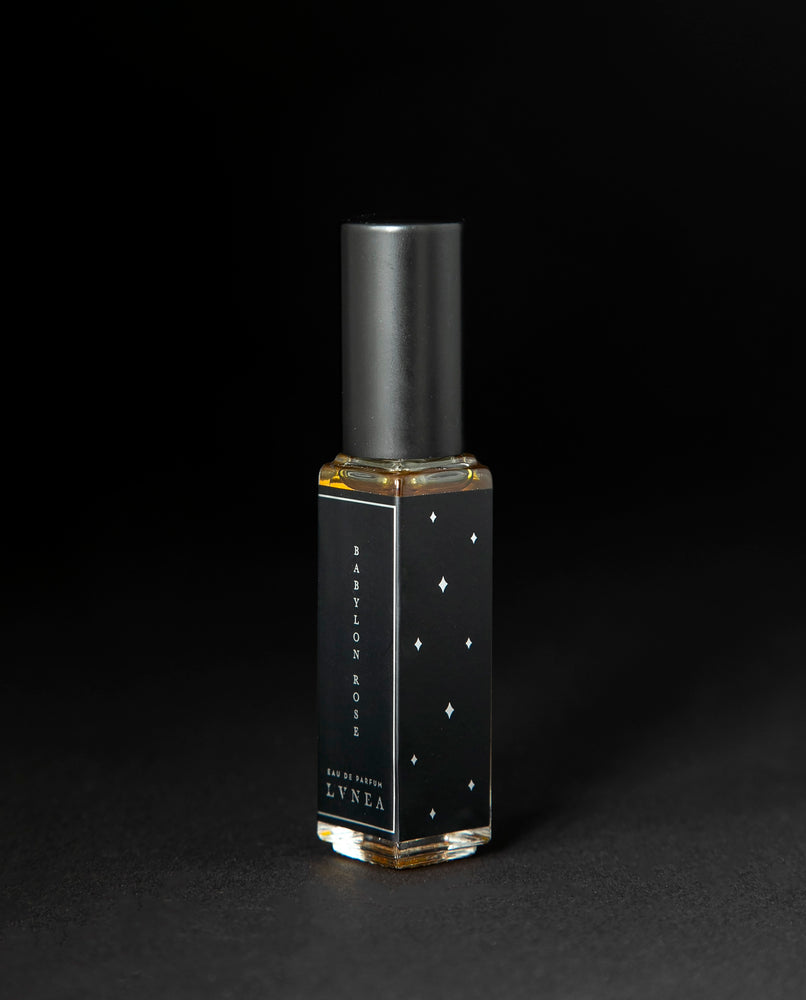 8ml clear glass bottle with black and silver label of LVNEA's limited edition Babylon Rose perfume on black background.