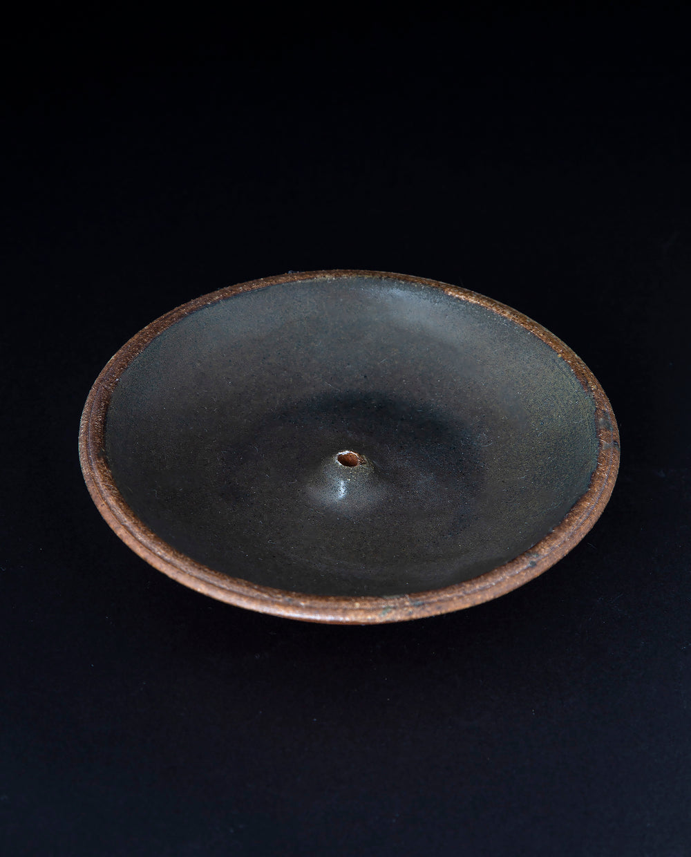 matte black glazed stoneware incense holder on black background