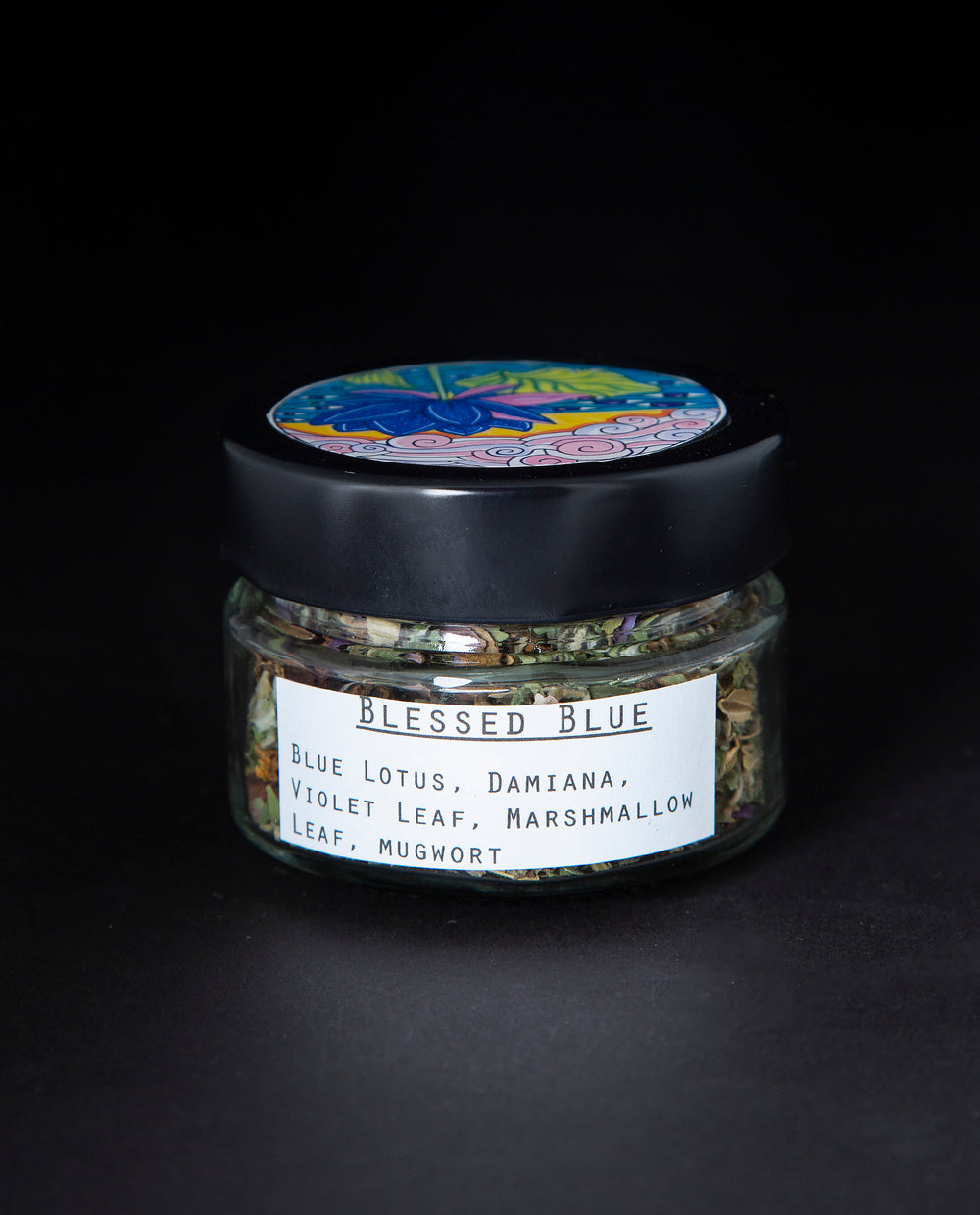 Clear glass jar with black lid containing a blue lotus herbal rolling blend. The white label reads 