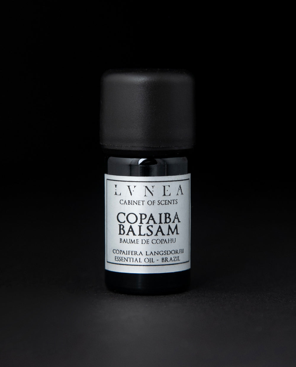 5ml black glass bottle with silver label of LVNEA's copaiba balsam essential oil on black background