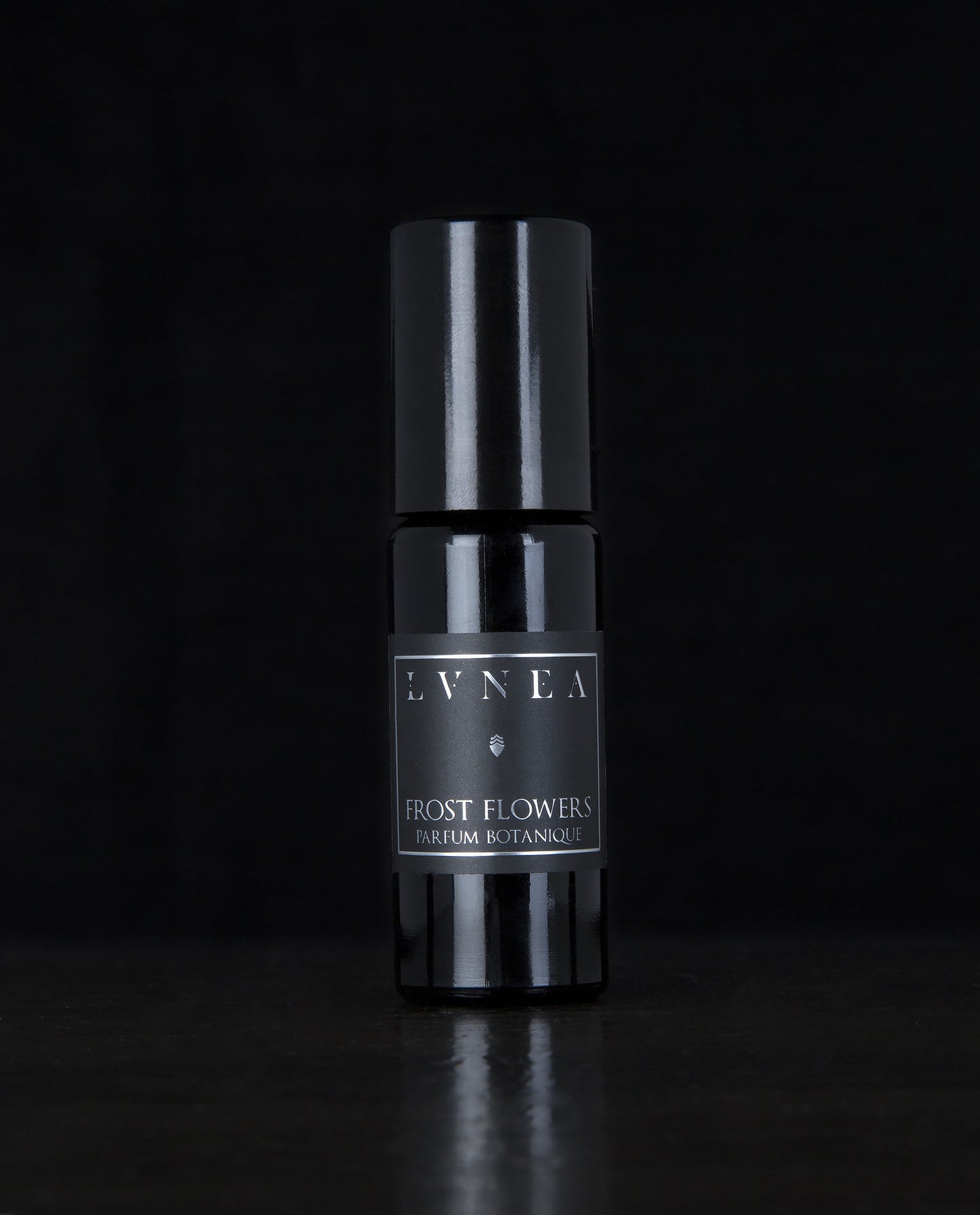 10ml black glass bottle of LVNEA's Frost Flowers natural roll on perfume oil on black background