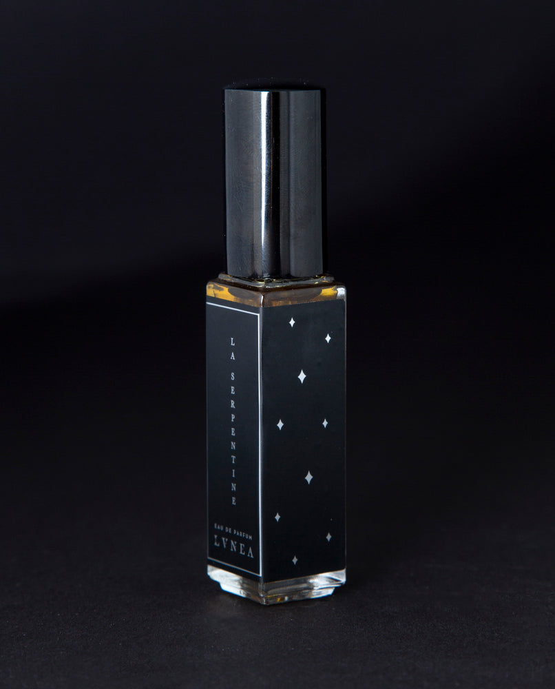 A fruity, leathery, unisex chypre fragrance by natural and botanical perfume brand LVNEA with notes of peach, osmanthus, patchouli, labdanum, and oakmoss. Presented in a 8ml star-spangled black glass bottle, the label reads LA SERPENTINE EAU DE PARFUM. 