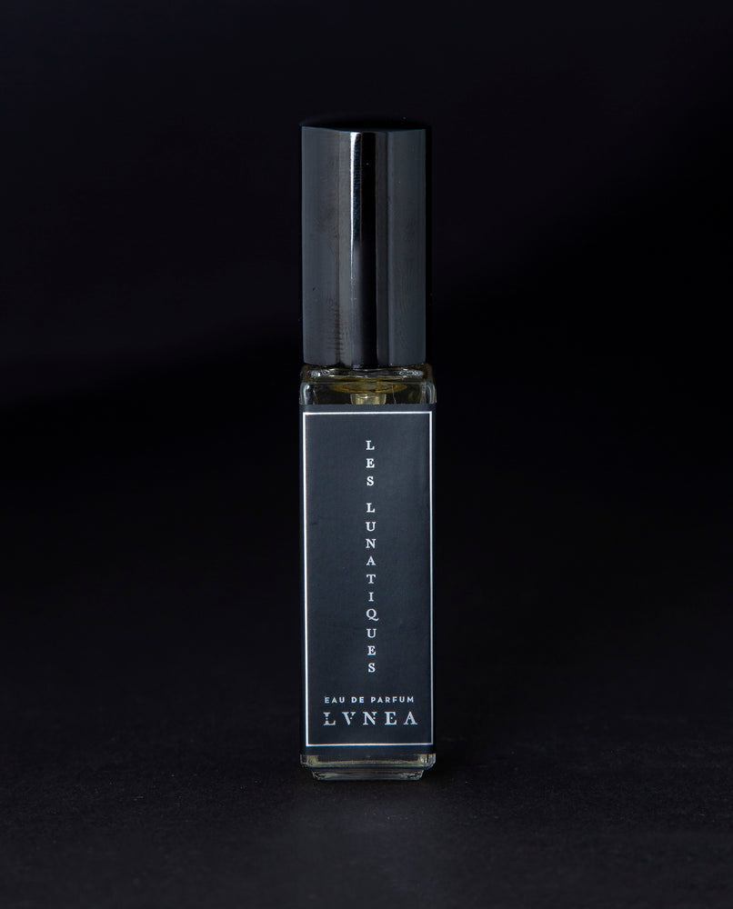 8ml clear glass bottle of LVNEA’s Les Lunatiques natural perfume on black background, bottle is rotated at a 3/4 angle exposing a star pattern on the label.