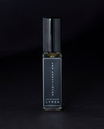 8ml clear glass bottle of LVNEA’s Les Lunatiques natural perfume on black background, bottle is rotated at a 3/4 angle exposing a star pattern on the label.