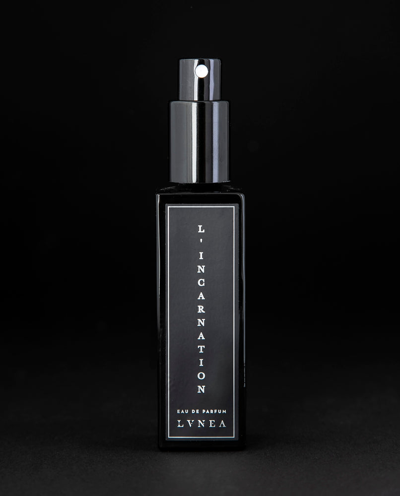 8ml clear bottle of LVNEA'S L'Incarnation natural perfume on black background, bottle is rotated at a 3/4 angle exposing a star pattern on the label.