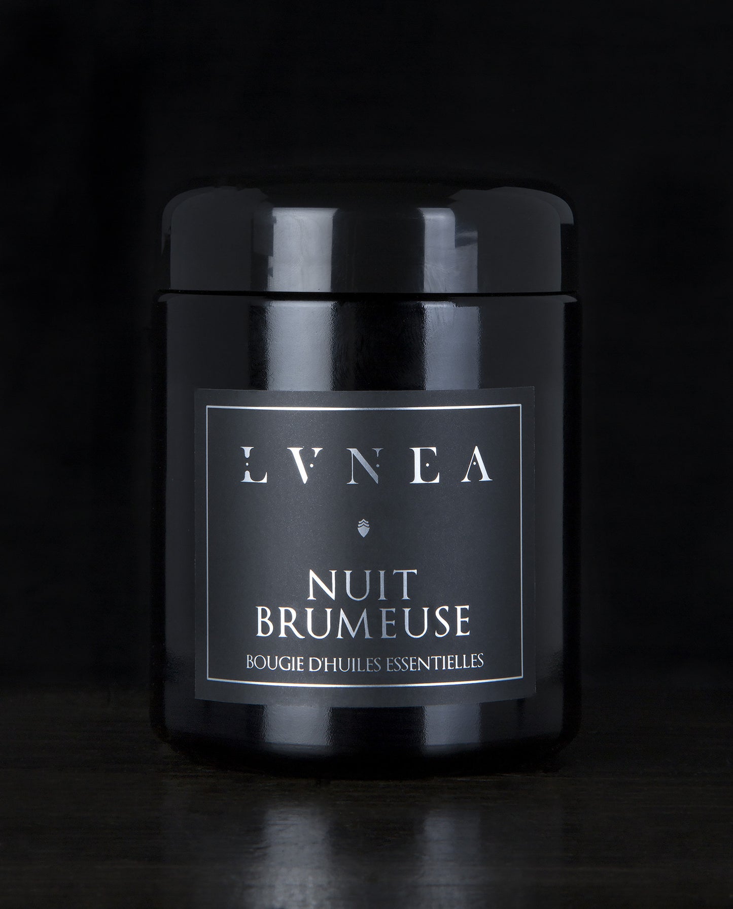 LVNEA’s Nuit Brumeuse candle housed in a resealable 8 ounce black glass jar on a black background