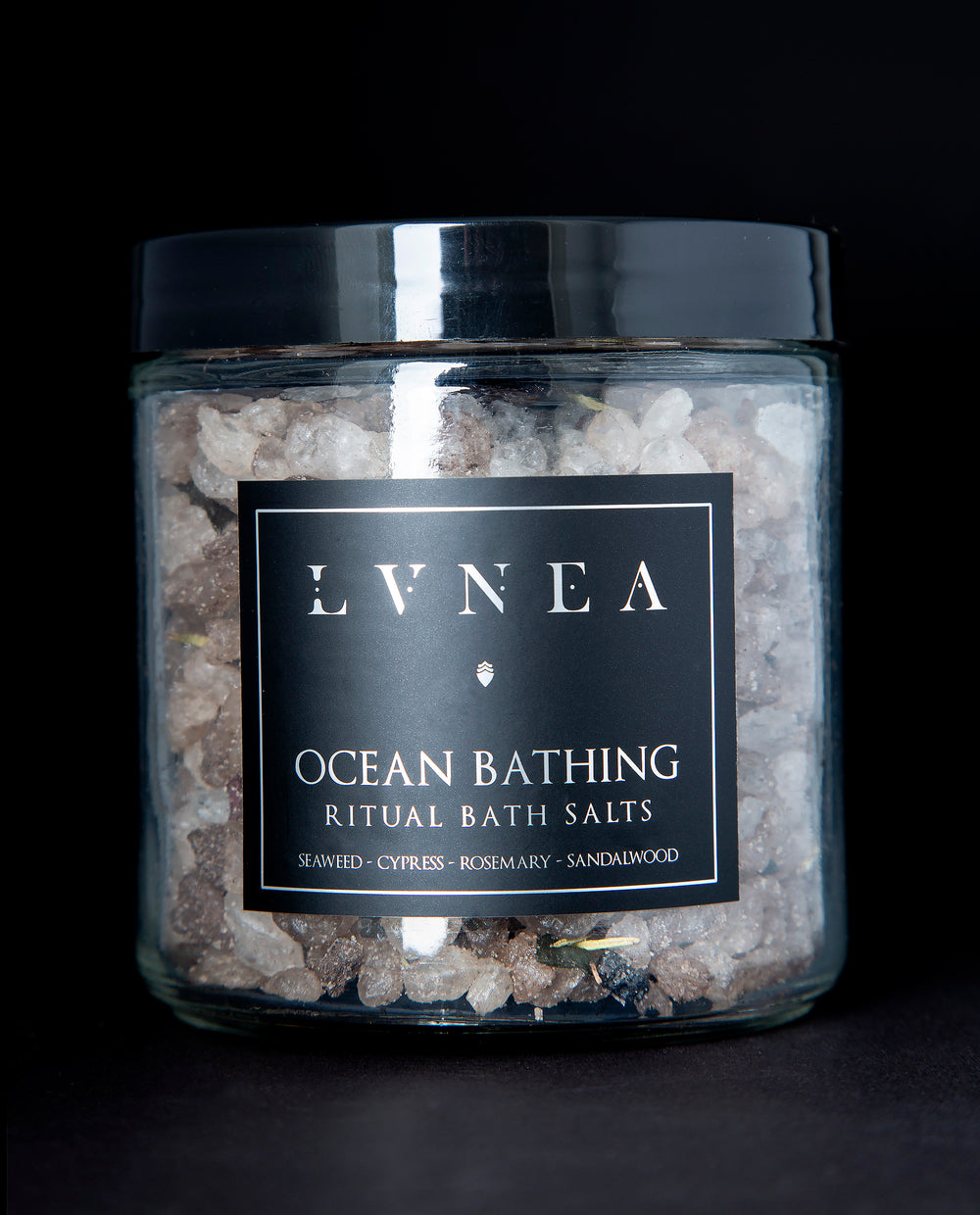 A clear 16 ounce jar filled with LVNEA's Ocean Bathing bath salts on black background