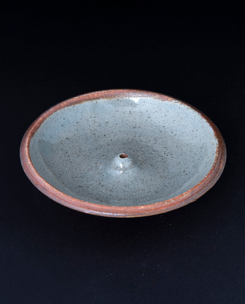 cream coloured glazed stoneware incense holder on black background